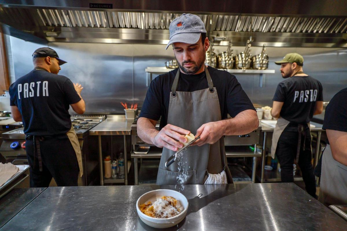 Chef Juan Manuel Umbert grates cheese onto a plate of pappardelle at his restaurant Pasta in Wynwood.