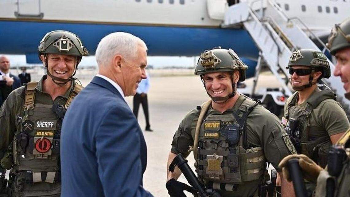 Broward Sheriff’s Office Sgt. Matt Patten, left, was photographed wearing a “QAnon” conspiracy patch on his official uniform while greeting Vice President Mike Pence in South Florida on Friday. The photograph, published online by Pence’s official Twitter account, was soon deleted.