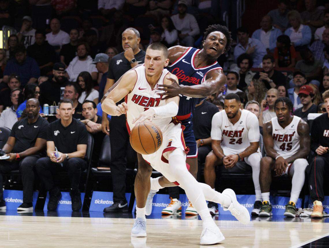 Los Angeles Clippers guard Kobe Brown (24) reaches around Miami Heat guard Tyler Herro (14) during the third quarter of a game on Monday, Dec. 1, 2025, at Kaseya Center in Miami, Fla.