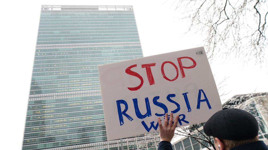 A protester holds a sign outside U.N. headquarters, Friday, Feb. 25, 2022, in New York. (AP Photo/Jeenah Moon)