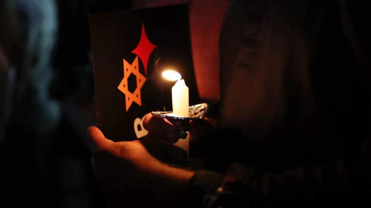 People hold candles as they gather together for a community-wide solidarity vigil in Miami Beach to remember victims of the 2018 mass shooting at a Pittsburgh temple.