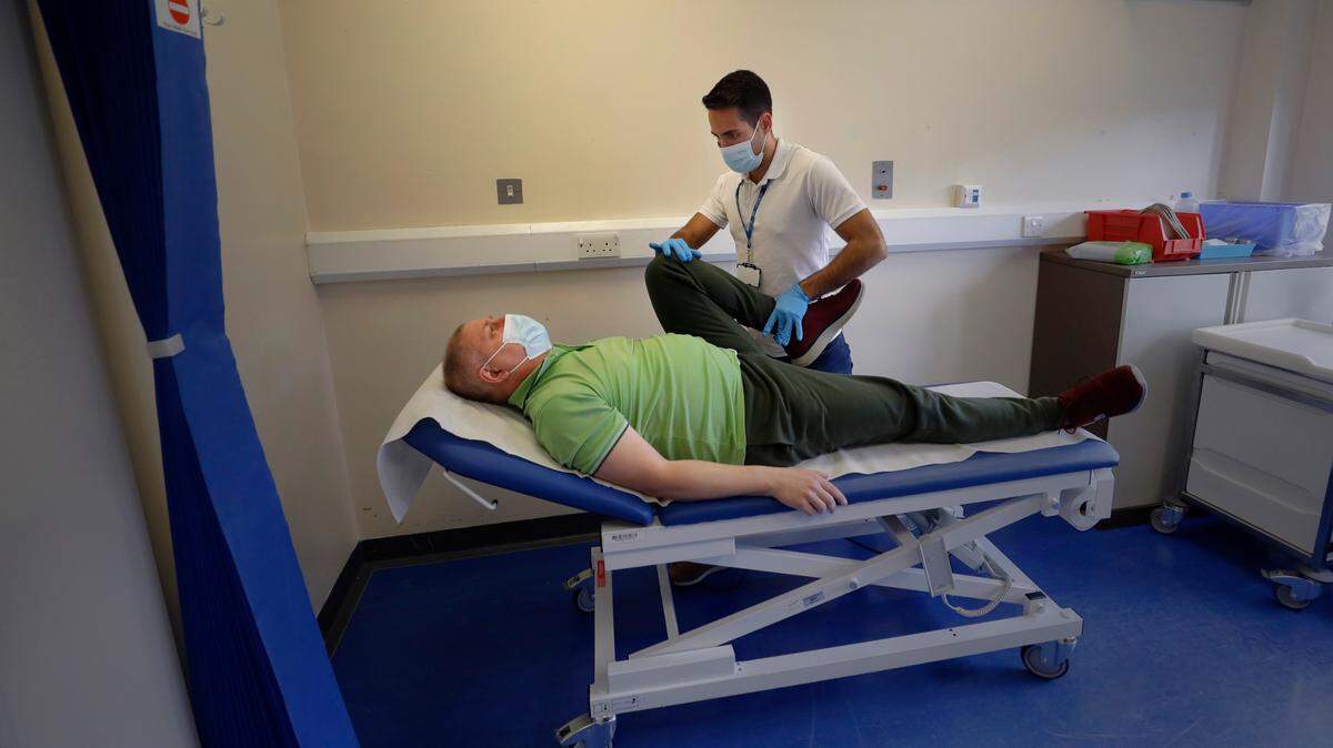 In this stock photo, long COVID patient Gary Miller receives treatment from physiotherapist Joan Del Arco at the Long COVID Clinic at King George Hospital in Ilford, London, Tuesday, May 11, 2021.