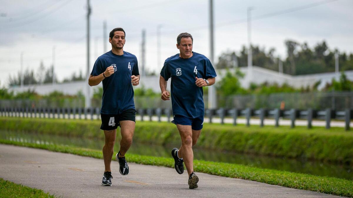 Martín Langesfeld, de 24 años, y su padre, Pablo Langesfeld, de 56, trotan por el Turnpike Trail en Doral, Florida, el 26 de enero de 2022.  Martín y Pablo correrán en el Maratón de Miami en honor a Nicole Langesfeld y su esposo, Luis Sadovnic, ambos fallecidos en el derrumbe del edificio de condominios de Surfside.