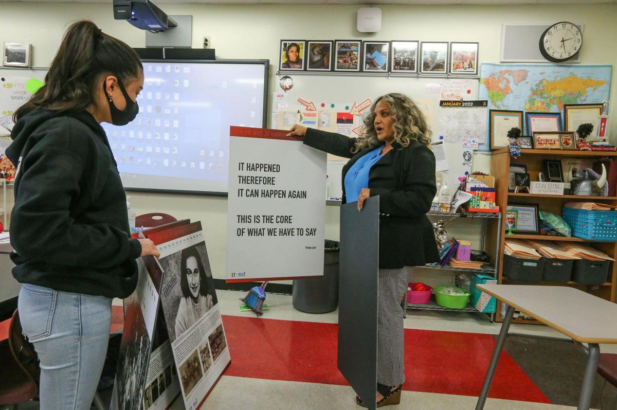 Norland Senior High School teacher Renee O’Connor prepares to display posters about the Holocaust as she speaks with student Catherine Ngunen, 17, in her classroom.  O'Connor is one of four finalists for Miami-Dade Schools Teacher of the Year.