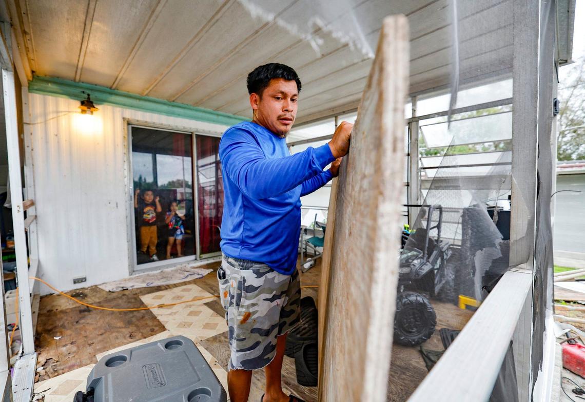 As Hurricane Milton approaches, Andres Alonso, 29, boards up his home as his children Jeycol Alonso, 3, Gael Alonso, 2, watch through their glass door at Fairmont Mobile Home Estates in Ruskin, Florida on Tuesday, October 8, 2024.