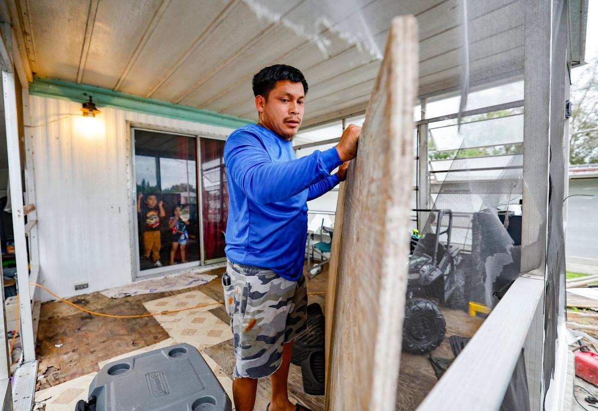 As Hurricane Milton approaches, Andres Alonso, 29, boards up his home as his children Jeycol Alonso, 3, Gael Alonso, 2, watch through their glass door at Fairmont Mobile Home Estates in Ruskin, Florida on Tuesday, October 8, 2024.