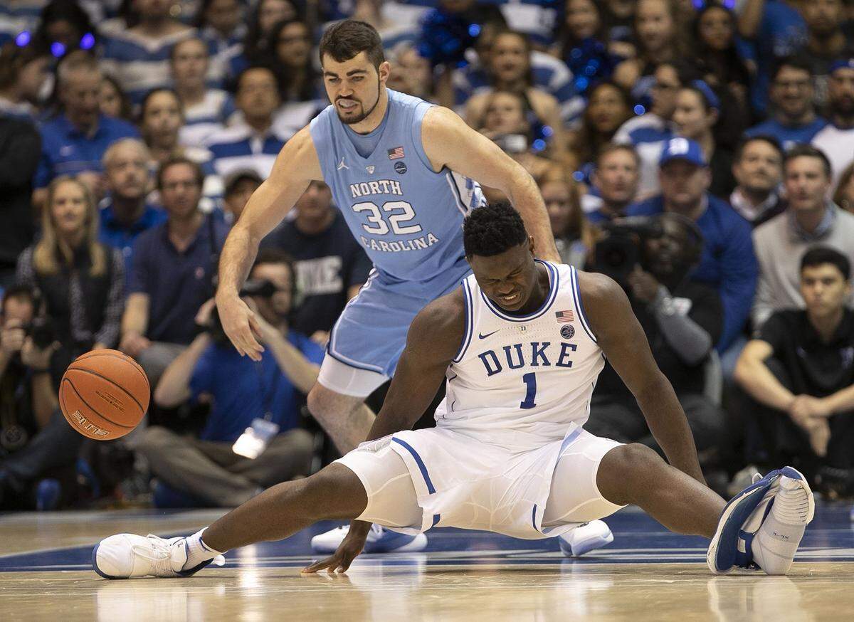 Duke’s Zion Williamson (1) falls to the court under North Carolina’s Luke Maye (32), injuring himself and damaging his shoe during the opening moments of the game in the first half on Wednesday, Feb. 20, 2019, at Cameron Indoor Stadium in Durham, N.C.
