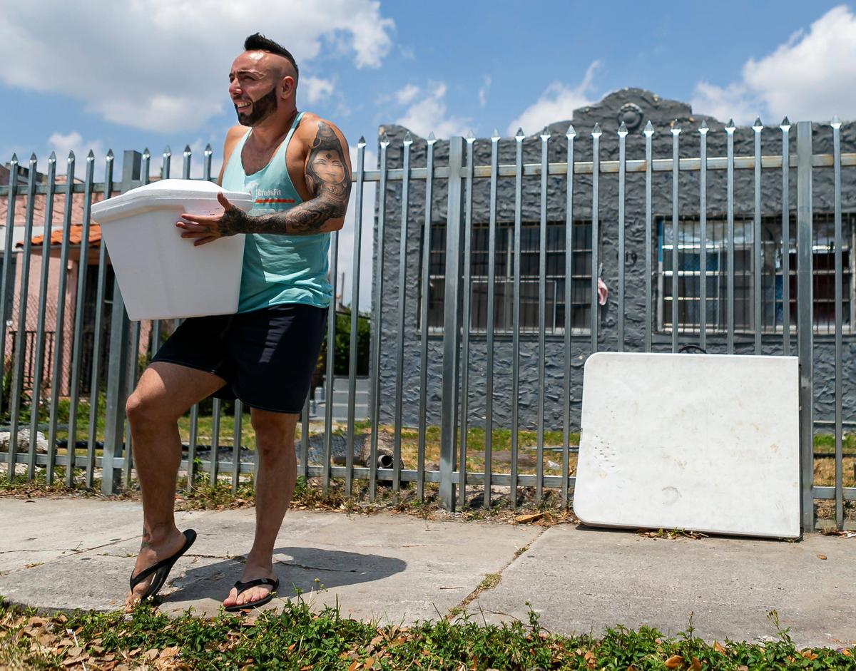 Jonatan Lopez, 33, carries some supplies from a friend, Kevin Cass, 30, outside of Lopez’s temporary home in Liberty City, Florida, on Friday, April 10, 2020. Lopez is part of a group of Argentinean tourists stranded in Miami after their flights home were canceled due to the coronavirus pandemic.