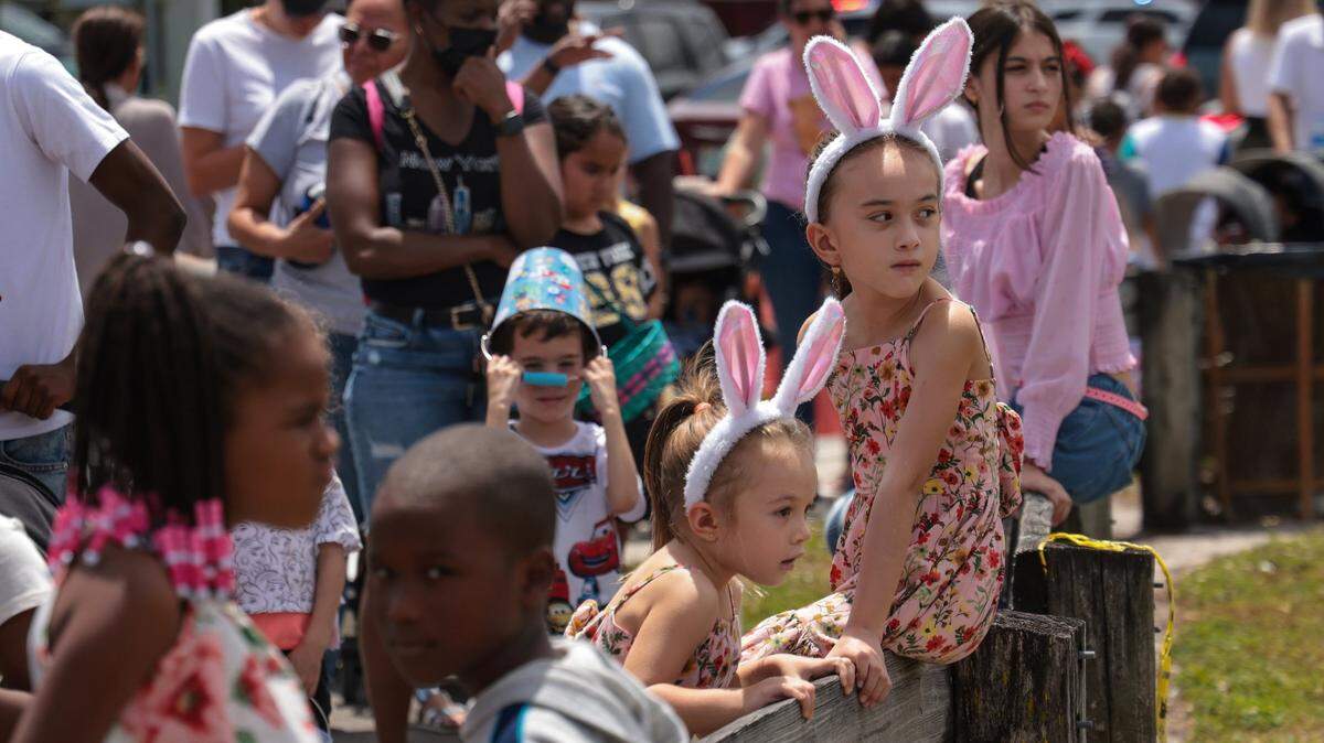 Two sisters lean on the fence as thousand of Easter revelers wait in line for entry to the Miami Gardens Easter Day Eggstravaganza at Miami Carol City Park to celebrate Easter Sunday on April 17, 2022.