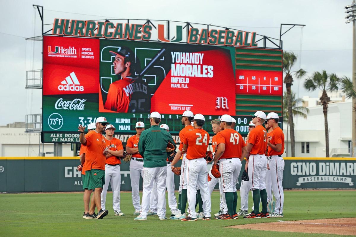 Miami Hurricanes pitching coach J.D Arteaga speaks to the players under the shadow of the new scoreboard at the University of Miami’s Alex Rodriguez Park at Mark Light Field in Coral Gables on Monday, February 14, 2022.