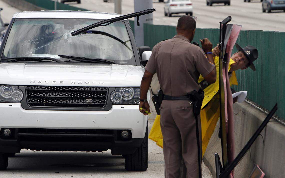 FHP Troopers (back to camera) Theodore Menner and Mark Wysocky look over debris at the scene where a large piece penetrated the windshield of a Range Rover traveling south on I-95 at Stirling Road this Tuesday, May 29, 2012