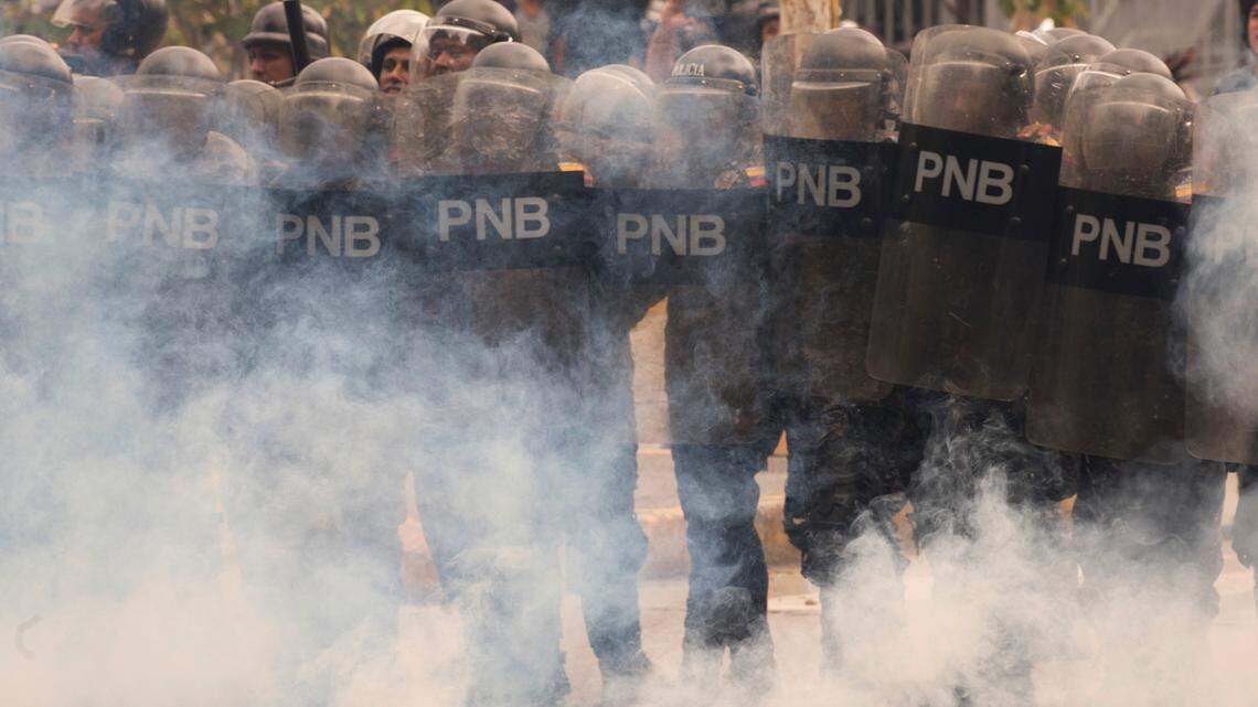 Riot police stand amid tear gas as they face off with student protesters from the Venezuela Central University demanding an increased budget for scholarships and to reopen the university cafeteria in Caracas, Venezuela, Wednesday, Nov. 21, 2018.