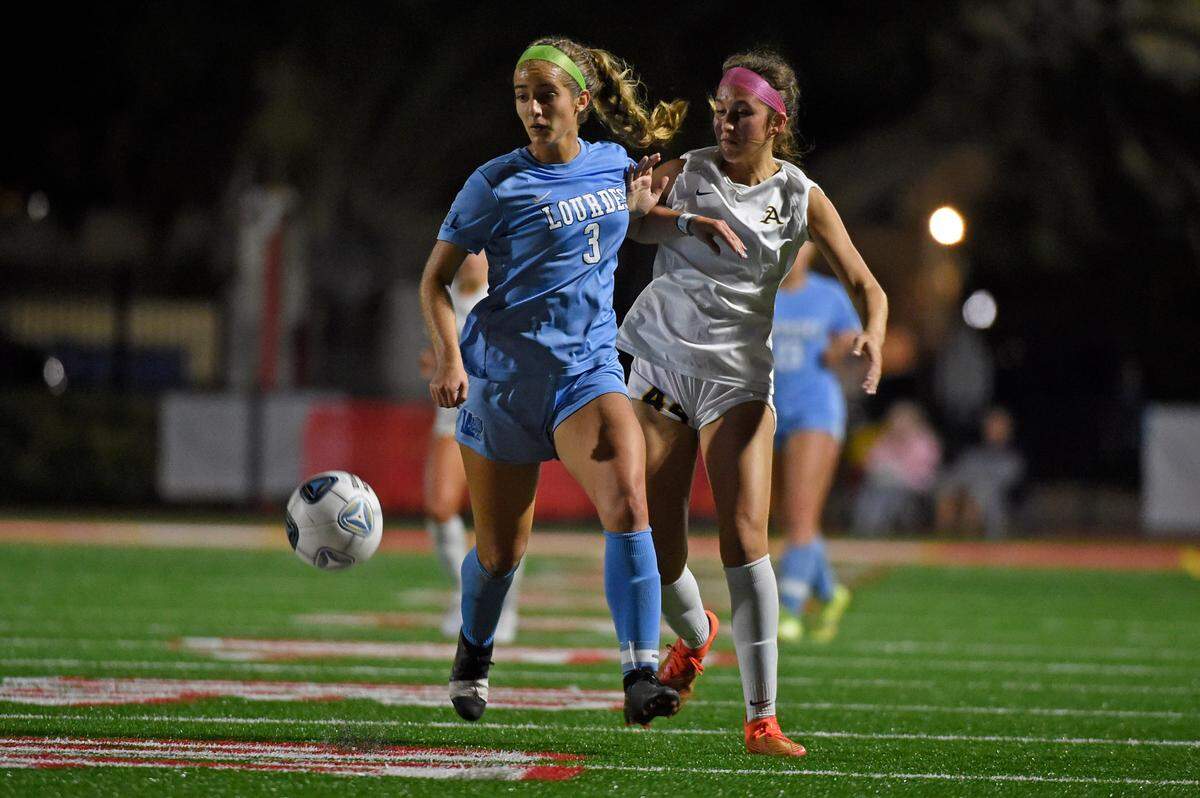 Lourdes junior Tessa Abreu looks for the ball with an Aquinas player marking her during the Bobcats’ 2-0 win over the Raiders on Tuesday night at Monsignor Pace High.