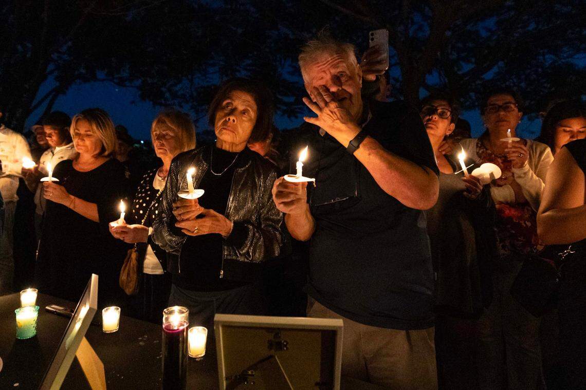 Community members react during a candlelight vigil Sunday, Feb. 23, 2025, honoring the victims of a triple murder that took place last Sunday morning at two homes in the Plum Bay community in Tamarac, Florida.
