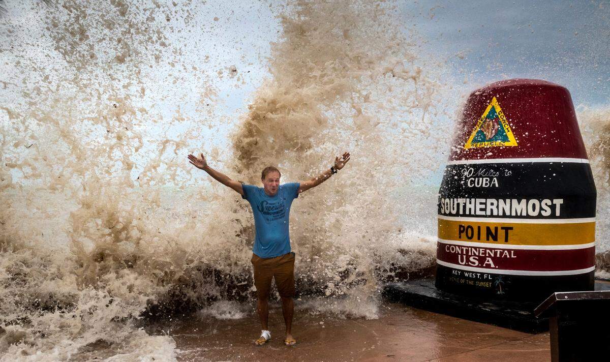 Sander Eshuis, a tourist from Holland, poses for a photo as he is doused by waves at the Southernmost Point marker in Key West, Florida, on Sept. 27, 2022. Sander and his wife, Lenneke, had never experienced a hurricane before and the proximity of Hurricane Ian to Key West allowed them to see some of the effects of the storm from a distance.