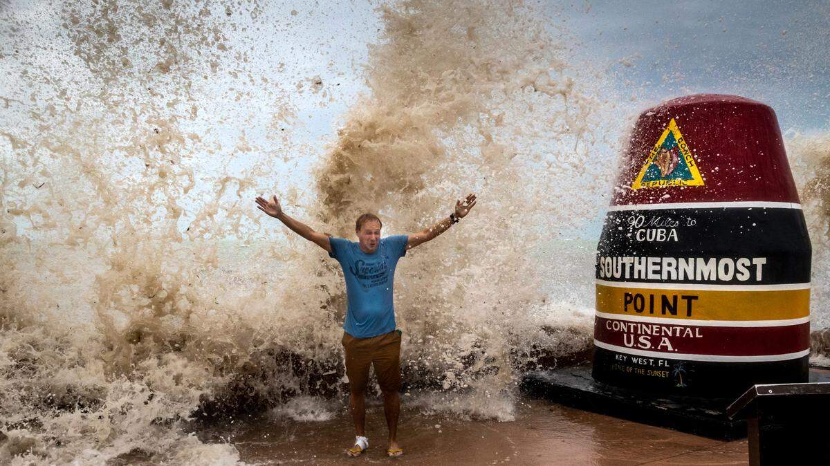 Sander Eshuis, a tourist from Holland, poses for a photo as he is doused by waves at the Southernmost Point marker in Key West, Florida, on Sept. 27, 2022. He and his wife, Lenneke, had never experienced a hurricane before and the proximity of Hurricane Ian to Key West allowed them to see some of the effects of the storm from a distance.