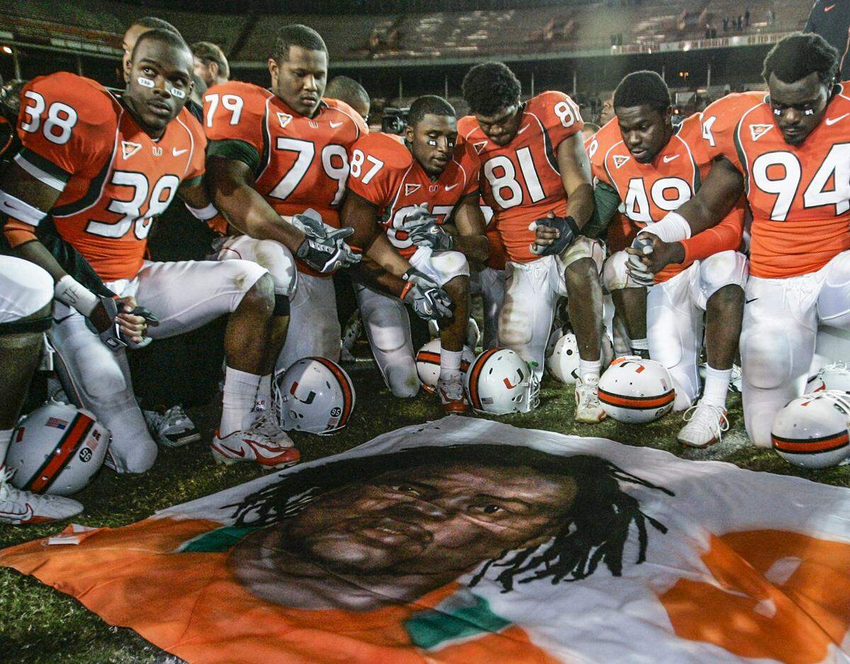 University of Miami football players, including Rashaun Jones (38) at left, hold hands at midfield in front of a mural of teammate Bryan Pata after a game against Boston College at the Orange Bowl Stadium in Miami on Nov. 23, 2006, the year Pata was murdered.