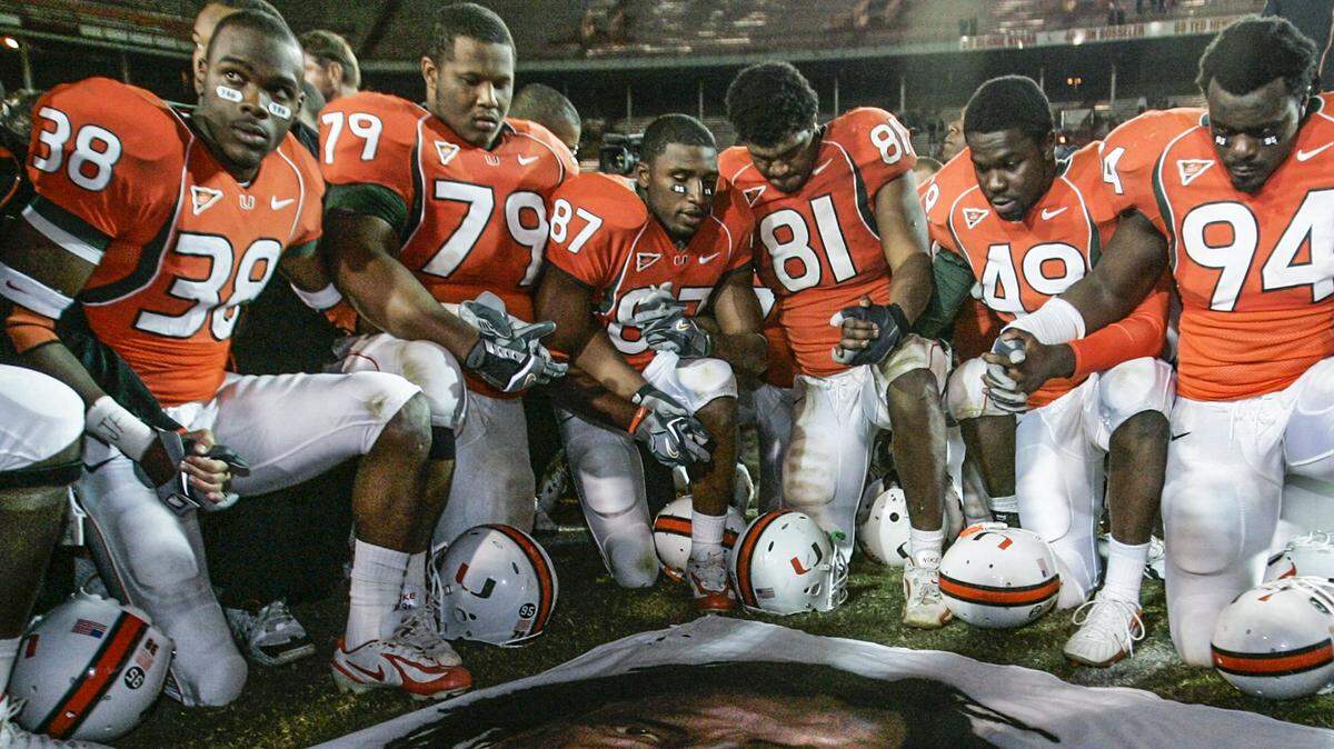University of Miami football players, including Rashaun Jones (38) at left, hold hands at mid-field in front of a mural of teammate Bryan Pata after game against Boston College at the Orange Bowl Stadium in Miami on November 23, 2006. Jones was arrested Thursday, August 19, 2021 in connection with the fatal shooting of his teammate, Bryan Pata.