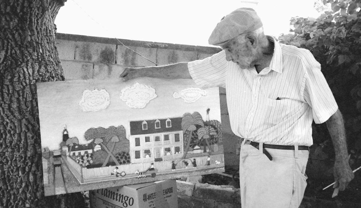 Key West artist Mario Sanchez with one of his whimsical works of art of old Key West.