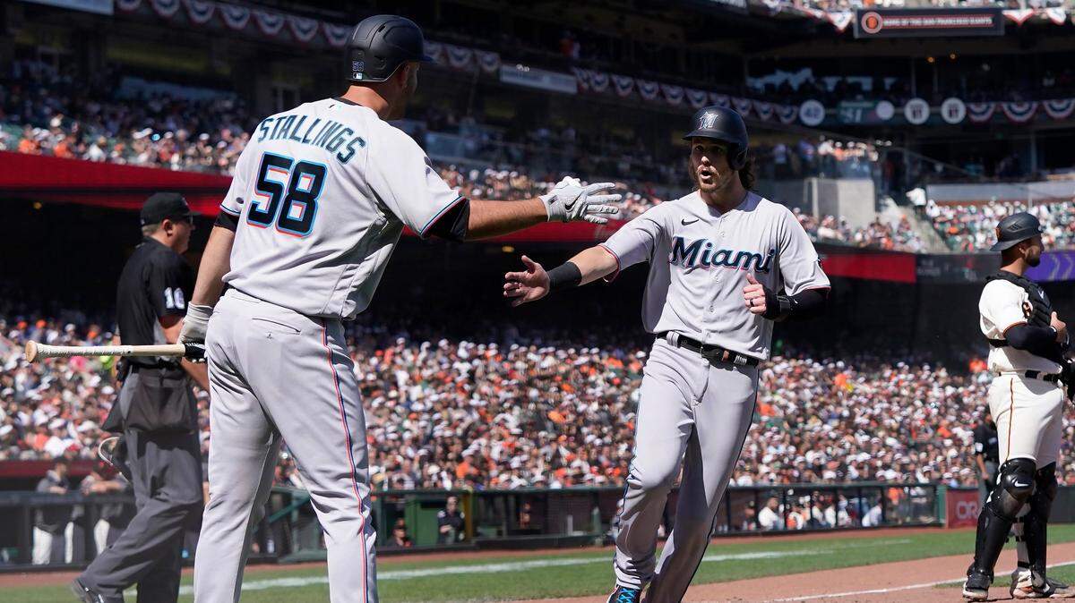 Miami Marlins’ Brian Anderson, right, is congratulated by Jacob Stallings (58) after scoring against the San Francisco Giants during the seventh inning of a baseball game in San Francisco, Saturday, April 9, 2022. (AP Photo/Jeff Chiu)