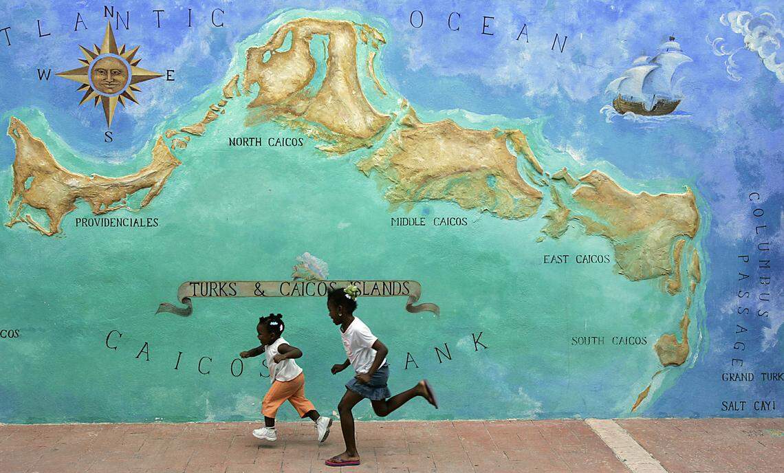 Two little girls race by a mural in Providenciales in the Turks and Caicos Islands. The deadly coronavirus has started to spread to other family islands in the British territory.