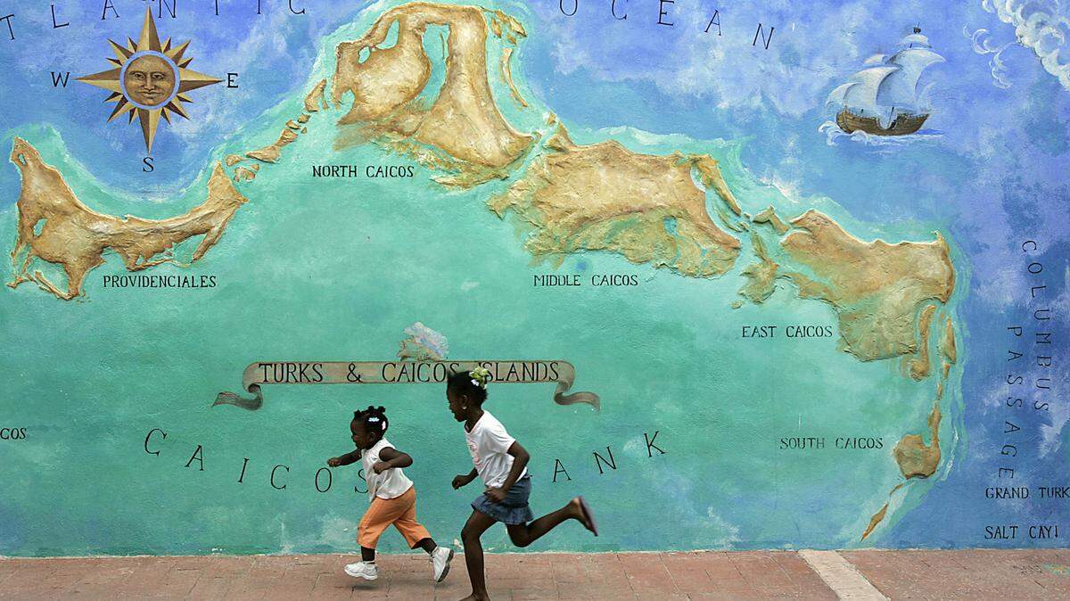 Two little girls race by a mural in Providenciales in the Turks and Caicos Islands. The deadly coronavirus has started to spread to other family islands in the British territory.