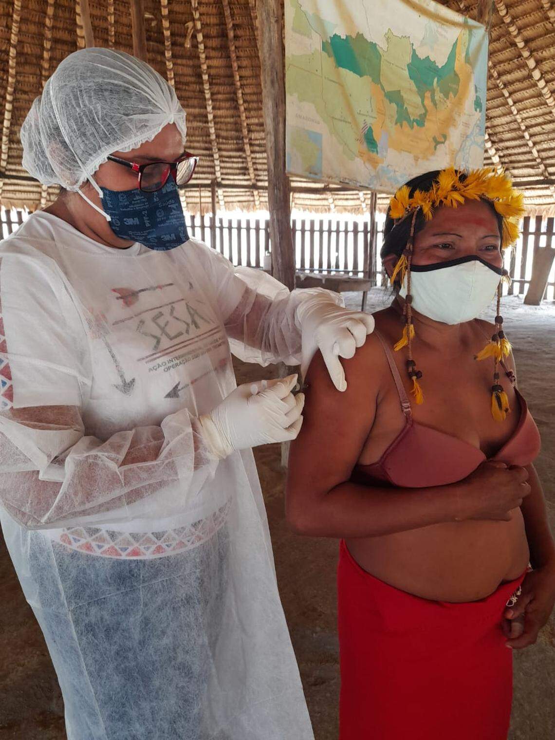 A Brazilian public health worker from SESAI, the indigenous health agency that’s part of the Health Ministry, administers a COVID-19 vaccine at a Tunayana village in the state of Pará, in the Amazon.