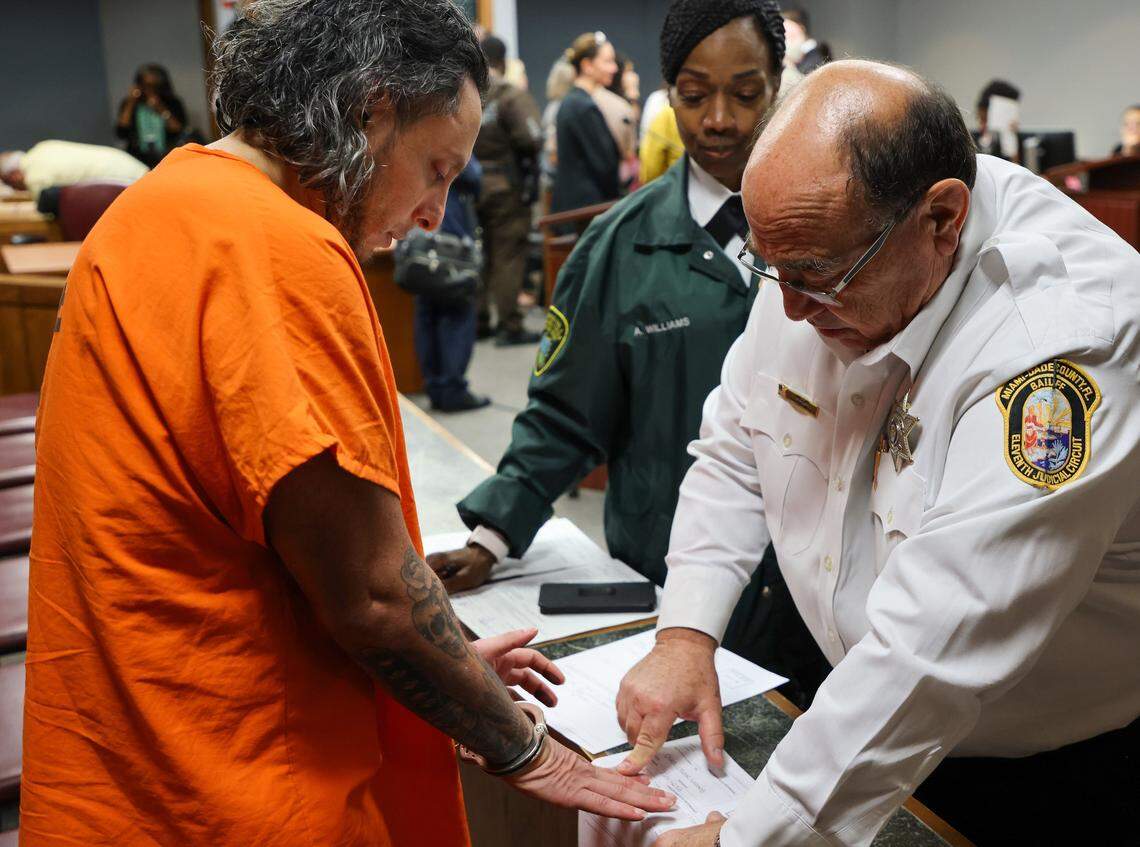 Oscar Olea, left, is fingerprinted inside Courtroom 7-2 at the Richard E. Gerstein Justice Building on Thursday, Aug. 21, 2025, in Miami, Florida. Miami-Dade Judge Alberto Milian ruled state prosecutors could not renege on Olea’s plea deal of 12 years in prison. Olea’s victims were dissatisfied with the deal.