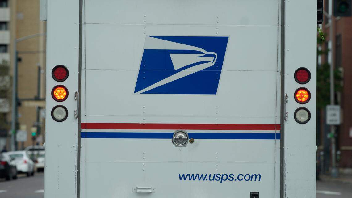 The logo adorns the back door of a United States Postal Service delivery vehicle as it proceeds westbound along 20th Street from Stout Street and the main post office Wednesday, June 1, 2022, in downtown Denver.