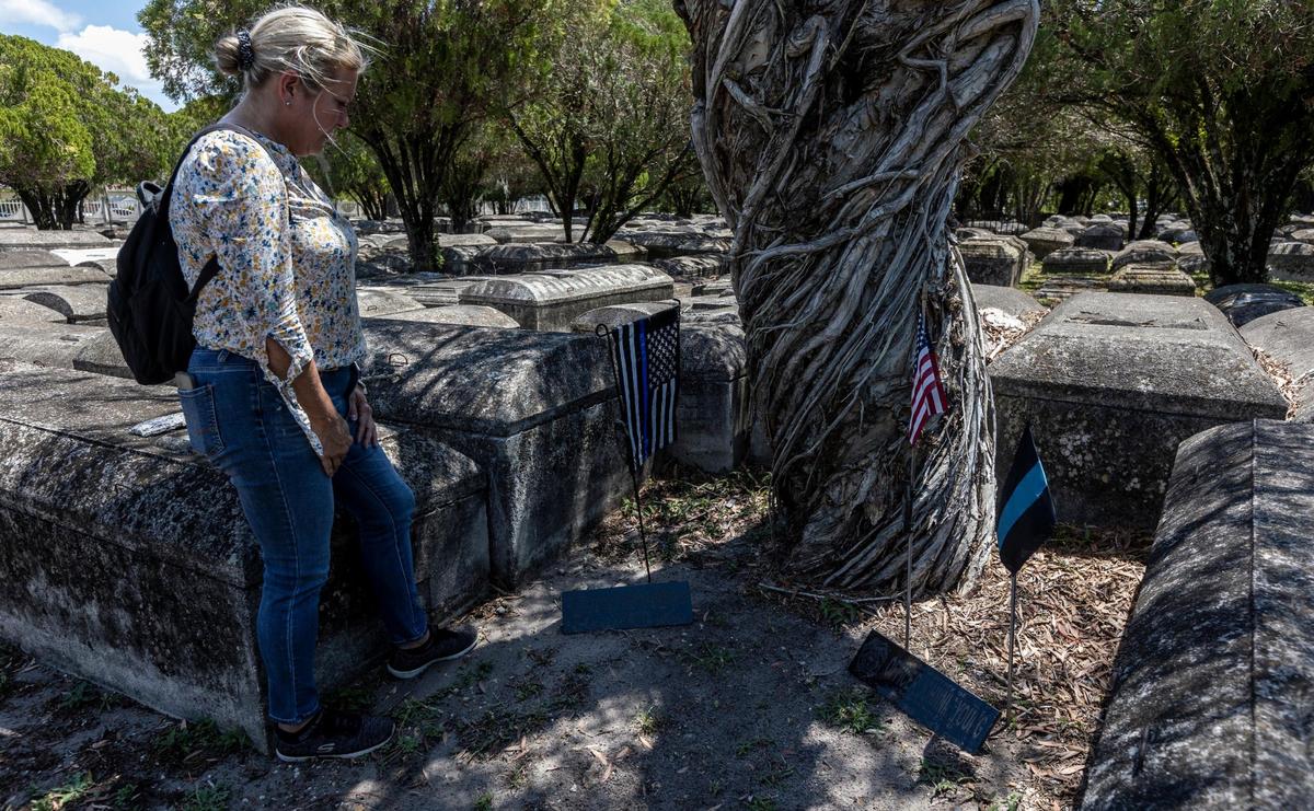 Miami, Florida, May 7 2021 - Retired Miami Detective Jerry Lynn Dellamico stands over makeshift memorials for City of Miami Officer Johnnie Young (right) and Metro Dade Officer Simmons Arrington at Evergreen Memorial Park in Allapatah.