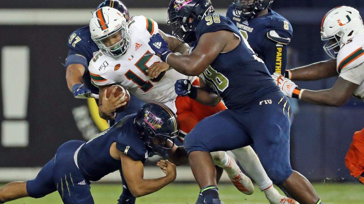 Miami Hurricanes quarterback Jarren Williams (15) is gang tackled y FIU defenders in the third quarter as the Florida International University Panthers host the University of Miami Hurricanes at Marlins Park in Miami on Wednesday, November 23, 2019.