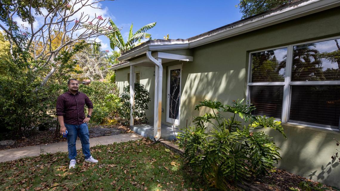Six years ago, Tanjim Hossain and his wife, Christine Oliver, bought their house in North Miami for $228,000. The residence sits on a corner lot dotted by palms. Above: On March 22, 2023, Tanjim Hossain pauses in his front yard next to his house in North Miami.