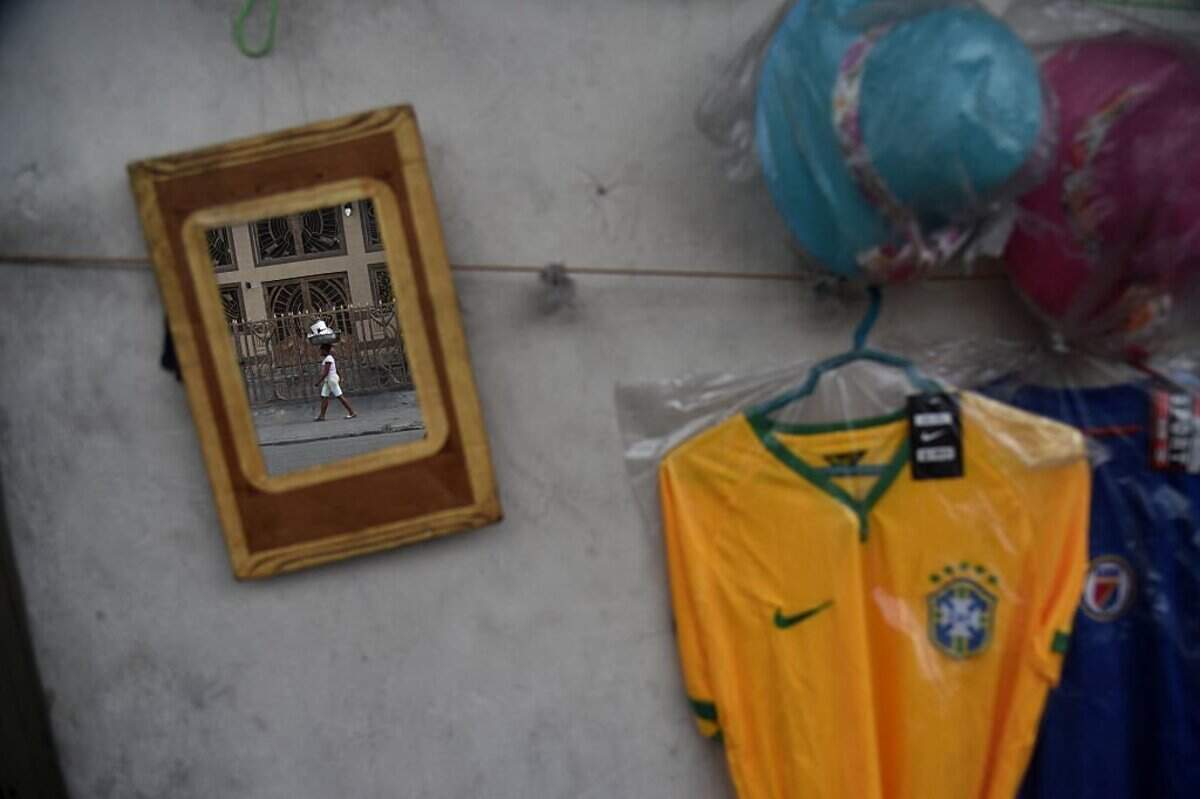 TOPSHOT - A woman is seen in a mirror on a wall in a stand selling football shirts next to a street, in Port-au-Prince on May 24, 2018. Haitians are fans of Brazil and Argentina football selections, which will soon participate in the Russia 2018 World Cup. (Photo by HECTOR RETAMAL / AFP via Getty Images)