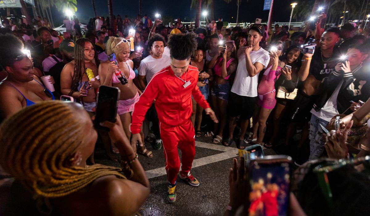 A man who only identified himself as Mark, center, performs a dance move for social media on Ocean Drive during spring break on Saturday, March 11, 2023, in Miami Beach, Fla.