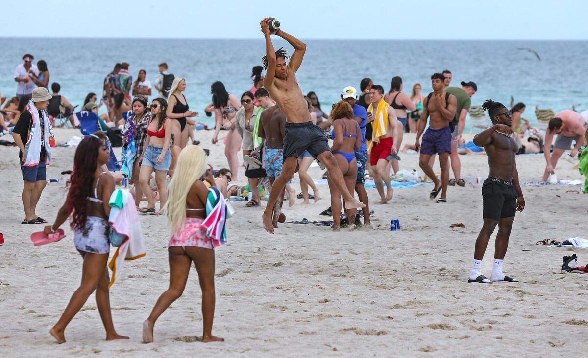 Spring Breaker Eliakim Brown, 23, of Florida National University catches a pass on a crowded section of South Beach on Thursday, March 17, 2022.