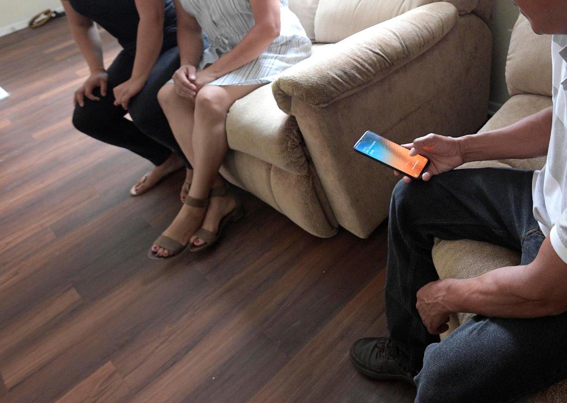 Servando, an undocumented migrant who was separated from his son at the southern border in 2018, receives a phone call while sitting with his family in their apartment, Sunday, Aug. 30, 2020, in Orlando.