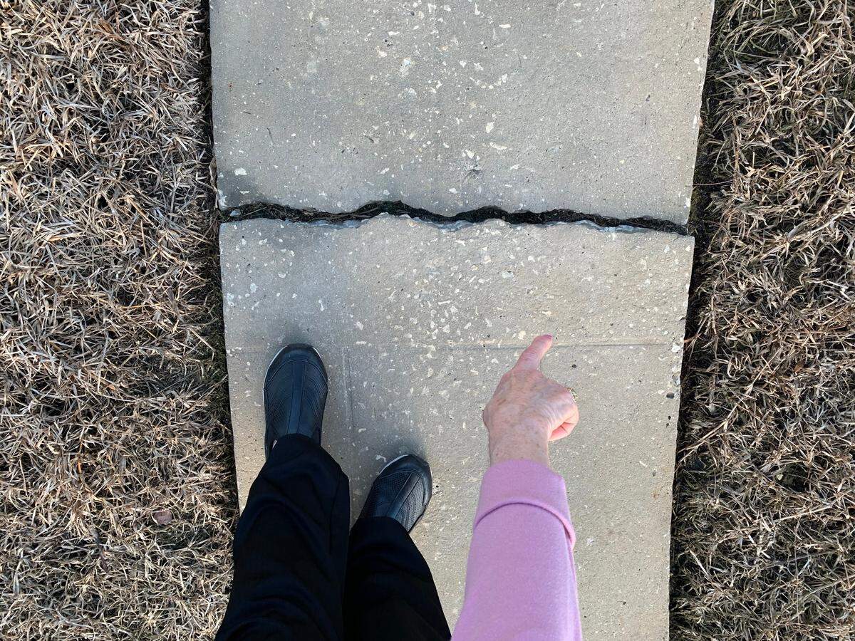 Daryle Prager, 81, points to the cracked concrete in her backyard sidewalk broken by this year’s King Tides. She said she doesn’t have much time before the rising water reaches her waterfront home in Surfside, so she’s forced to sell the house.