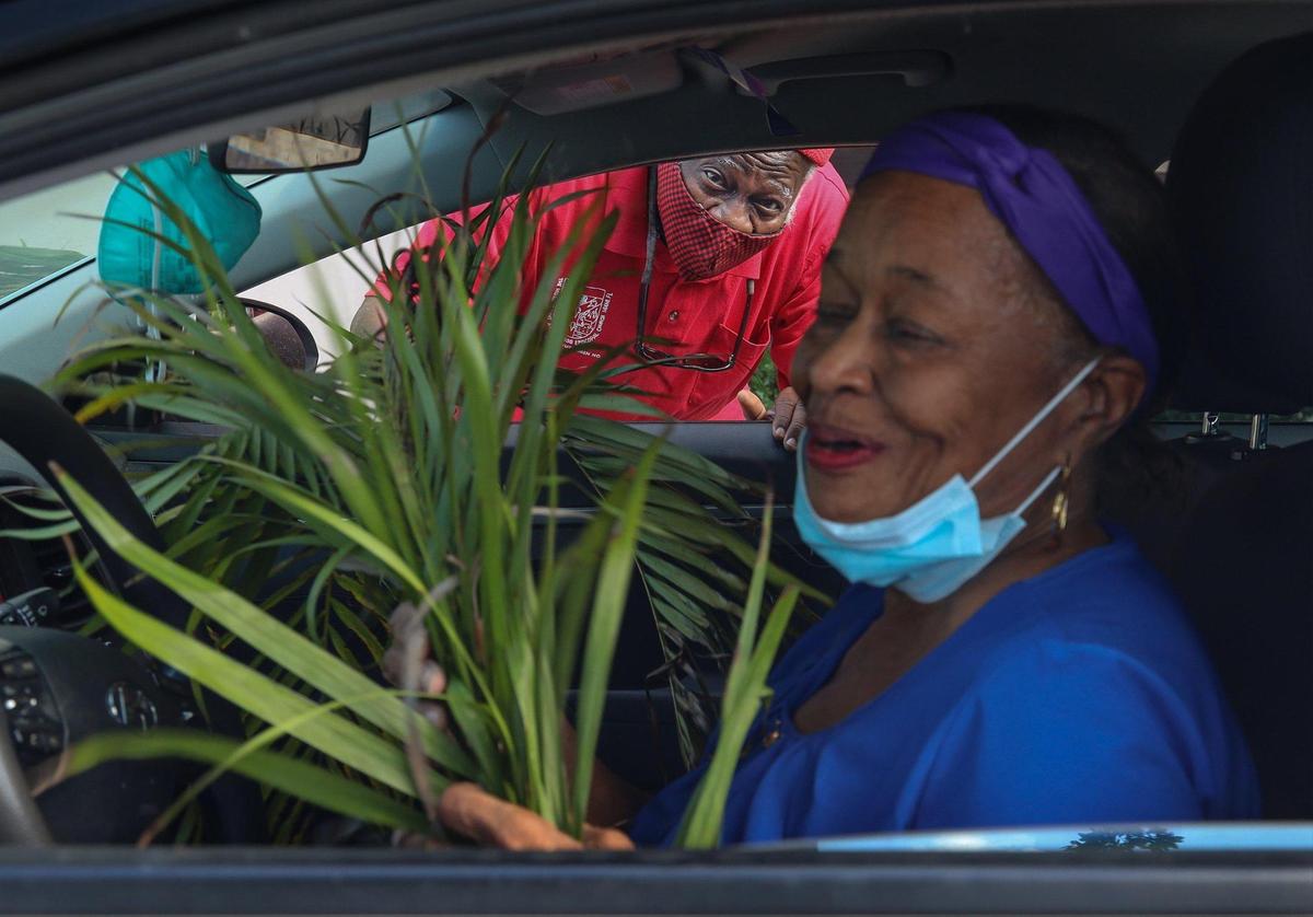 Enos Darling II, of North Miami Beach, left, hands palms to happy motorist on Sunday, March 28, 2021 Historic St. Agnes Episcopal Church held a drive-thru Palm Sunday event during the start of Holy Week in Miami’s Historic Overtown neighborhood.