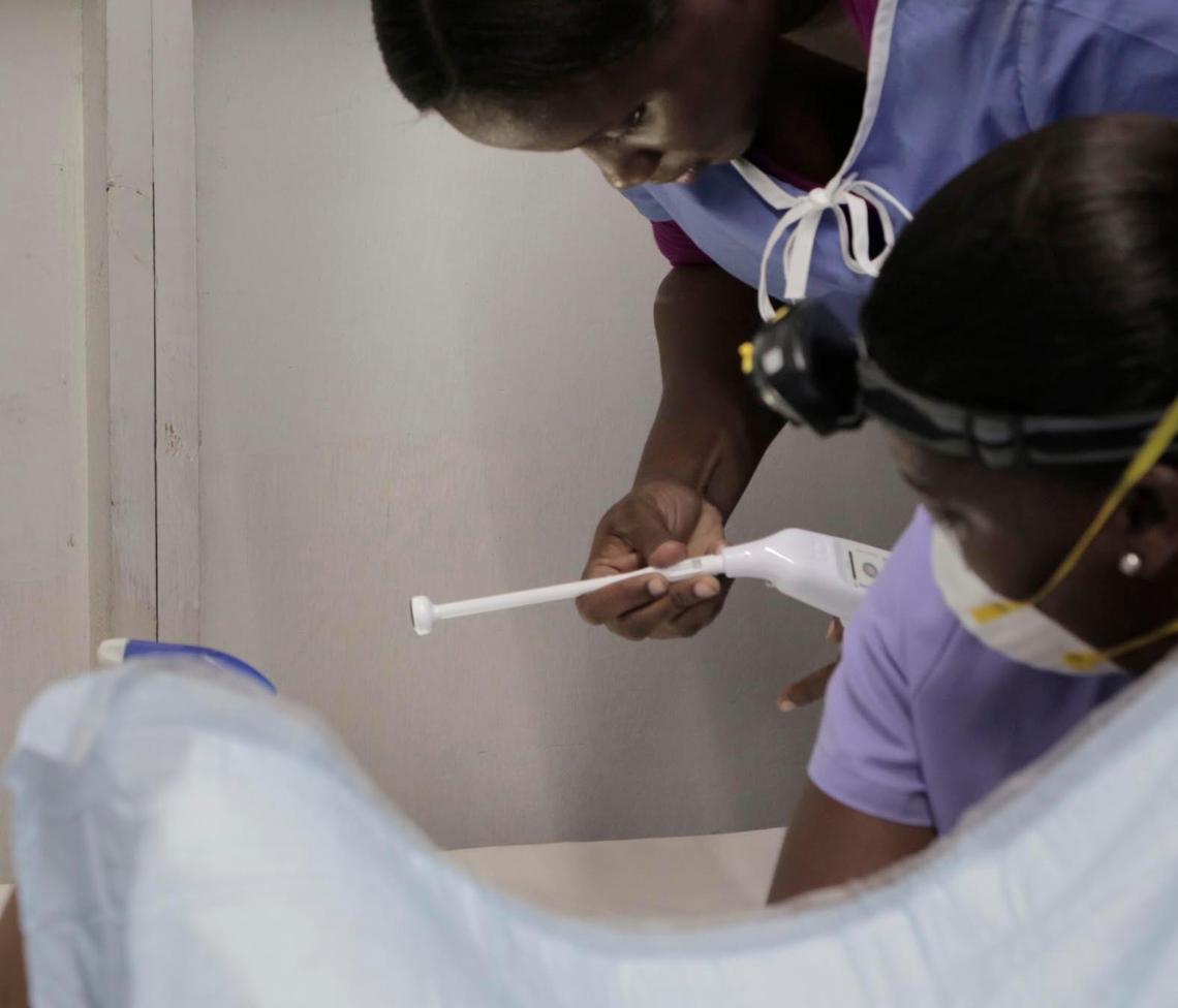 A medical worker attaches a sterilized probe to a heat gun as midwife Nanotte Louis (right), prepares to treat a precancerous lesion.
