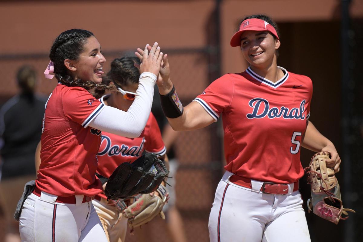 Doral Academy pitcher Alyssa Zabala, left, celebrates with first baseman Ana Richiez (5) the third inning of an FHSAA State Championship Softball Game against Melbourne, Saturday, May 28, 2022, in Clermont, Fla. (Phelan M. Ebenhack for the Miami Herald)