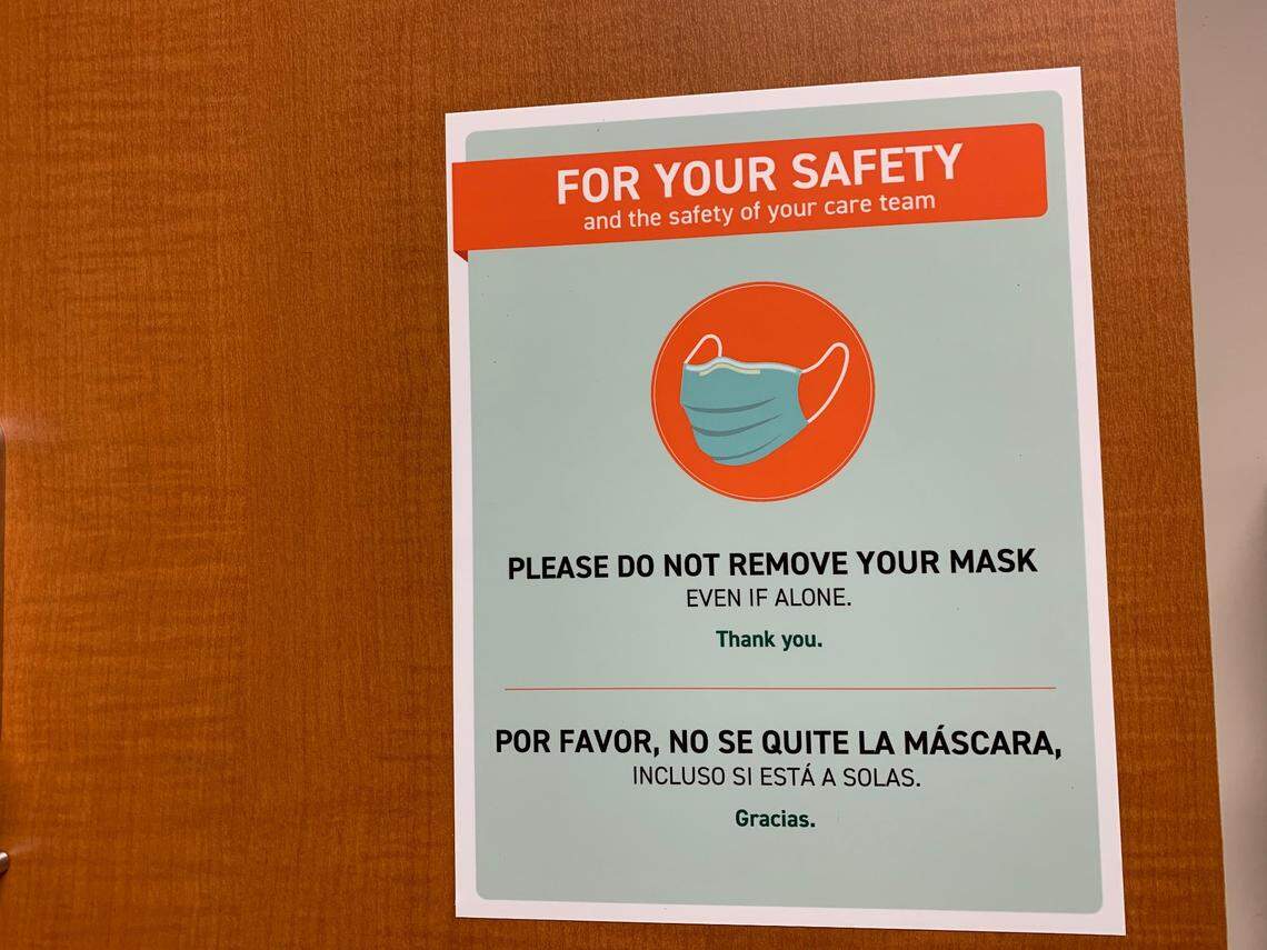 A sign inside an exam room at the University of Miami’s Lennar Foundation Medical Center asks that patients keep their masks on, even if they are alone in the room during the COVID-19 pandemic.