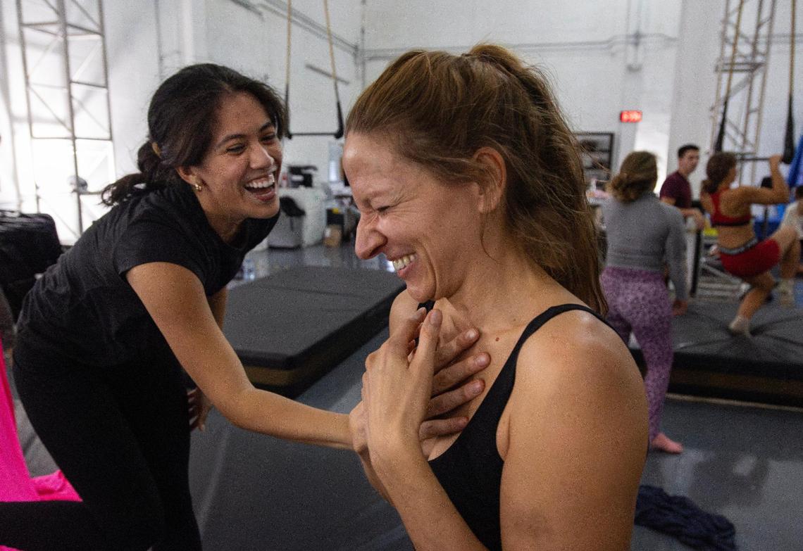Student Claudia Apaestegui, 25, and Mila Puletti laugh after Puletti tried to help her perform a combination on the silks unsuccessfully at the Miami Circus Arts Center on July 12, 2023, in Miami, Fla.