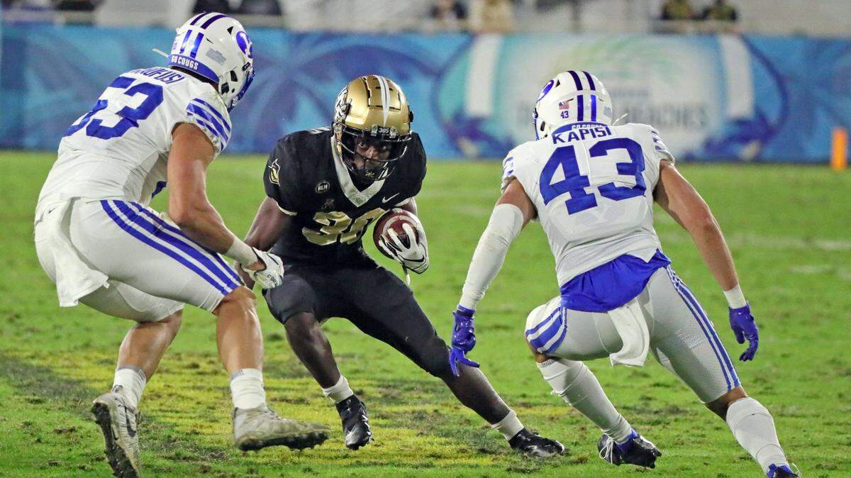 UCF Knights running back Greg McCrae (30) attempts to out maneuver Brigham Young Cougars linebacker Isaiah Kaufusi (53) and defensive back Jared Kapisi (43) in the first half at the Boca Raton Bowl 2020 at FAU Stadium in Boca Raton on Tuesday, December 22, 2020.
