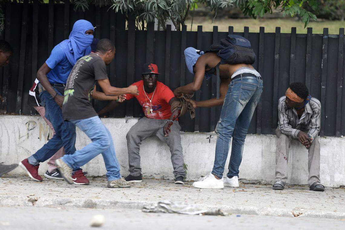 An off-duty police officer has his wound taken care of during and exchange of gunfire with army soldiers during a protest over police pay and working conditions, in Port-au-Prince, Haiti, Sunday, Feb. 23, 2020. Off-duty police officers and their supporters exchanged fire for nearly two hours with members of the newly reconstituted Haitian army in front of the national palace. (AP Photo/Dieu Nalio Chery)