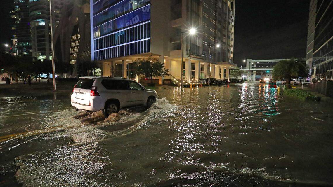 A car drives through a flooded Northeast 11th Street and Biscayne Boulevard in downtown Miami on Tuesday, Feb. 16, 2021.