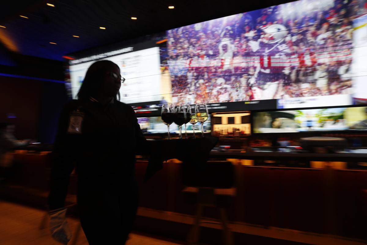 A waitress carries glasses of wine at a MGM Grand Detroit casino bar in Detroit, Wednesday, March 11, 2020.