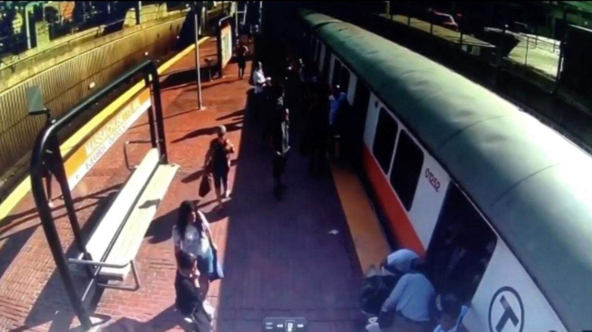 Surveillance video shows passengers rush to help a woman whose leg got caught between a train and a platform.