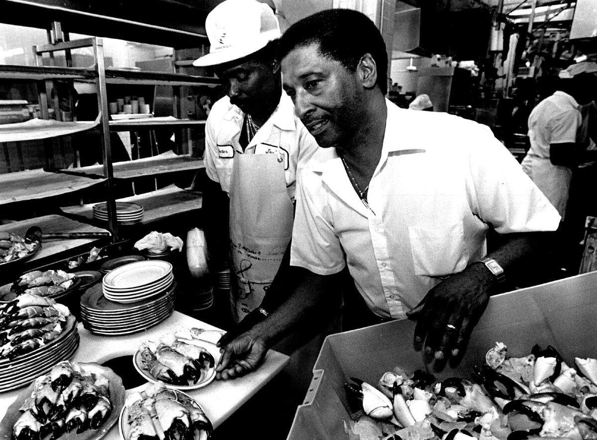 Calvin Keel, right, supervises the kitchen at Joe’s Stone Crab while Hector Rosales cracks crabs in 1992.
