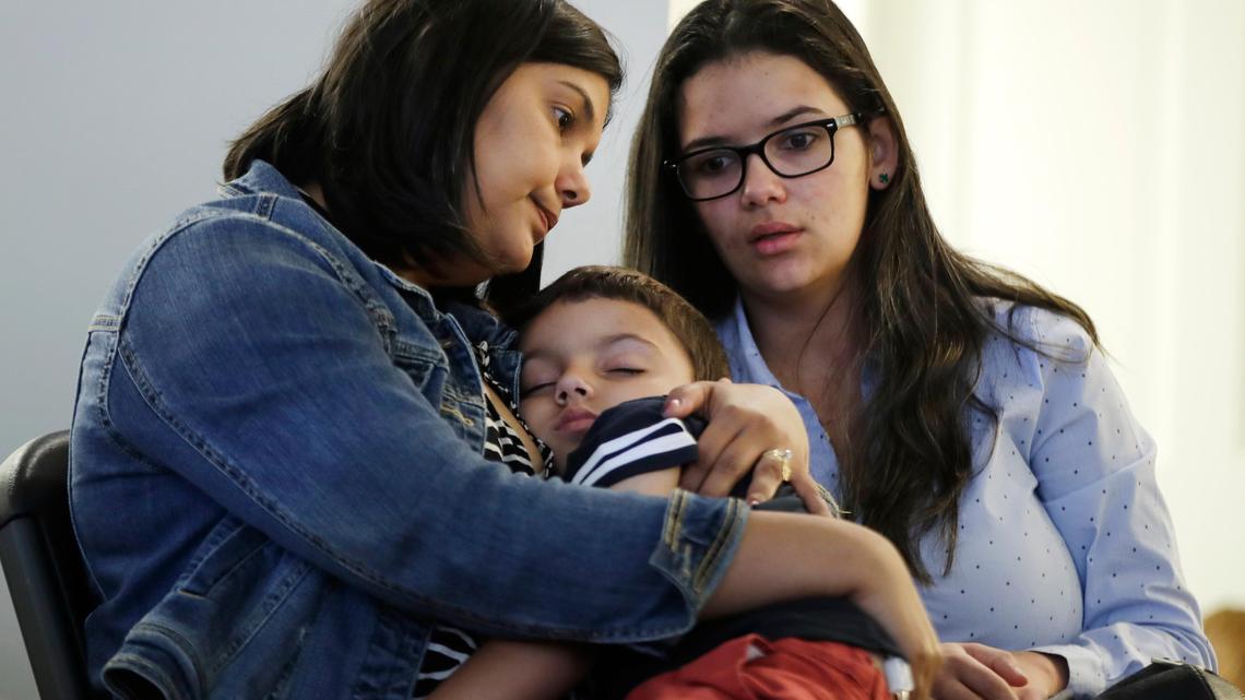 Sirlen Costa, of Brazil, holds her son Samuel, 5, as her niece Danyelle Sales, right, looks on during a news conference, Monday, Aug. 26, 2019, in Boston. Costa brought her son to the United States seeking treatment for his short bowel syndrome. Doctors and immigrant advocates say federal immigration authorities are unfairly ordering foreign born children granted deferred action for medical treatment to return to their countries.
