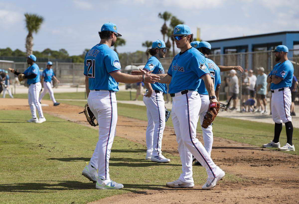 Miami Marlins third baseman Graham Pauley (21) and left fielder Griffin Conine (18) interact during the team’s first full-squad spring training workout at Roger Dean Stadium on Monday, Feb. 16, 2026, in Jupiter, Fla.